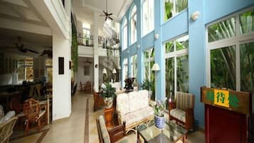 A spacious indoor area with a high ceiling, a staircase, and a seating area with a table and chairs.