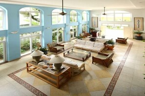 A spacious living room with a large sofa, coffee table, and chairs, featuring large windows and a tiled floor. - Venus Garden Villa(Sanya Dadonghai Summer Department) (Sanya)