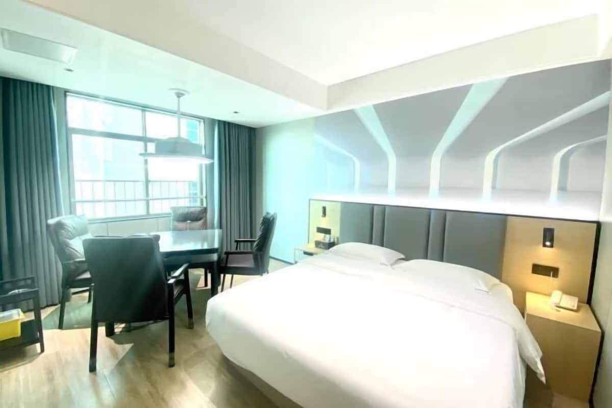 A hotel room with a bed, a desk, a chair, and a window.