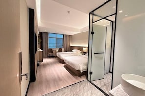 Une chambre d’hôtel avec un grand lit, une salle de bain séparée avec une baignoire, un bureau avec une chaise et une vue sur l’extérieur.