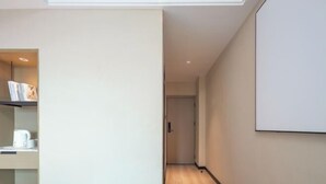 A hallway with a bookshelf, a door, and a wall-mounted screen. - Haikou Meizhiyuesu Hotel (Farming Middle School) (Haikou)