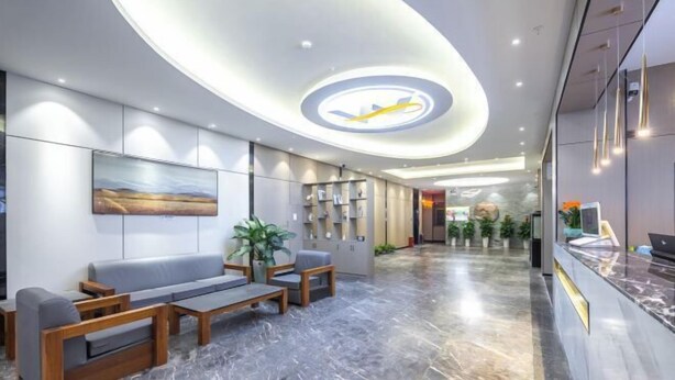 A modern hotel lobby with a reception desk, seating area, and a unique ceiling design. - Haikou Meizhiyuesu Hotel (Farming Middle School) (Haikou)