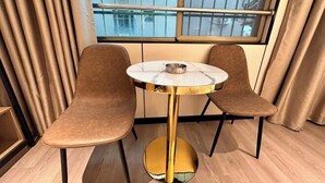 A room with a round table, two chairs, a window with a view, and curtains. - Haikou Meizhiyuesu Hotel (Farming Middle School) (Haikou)