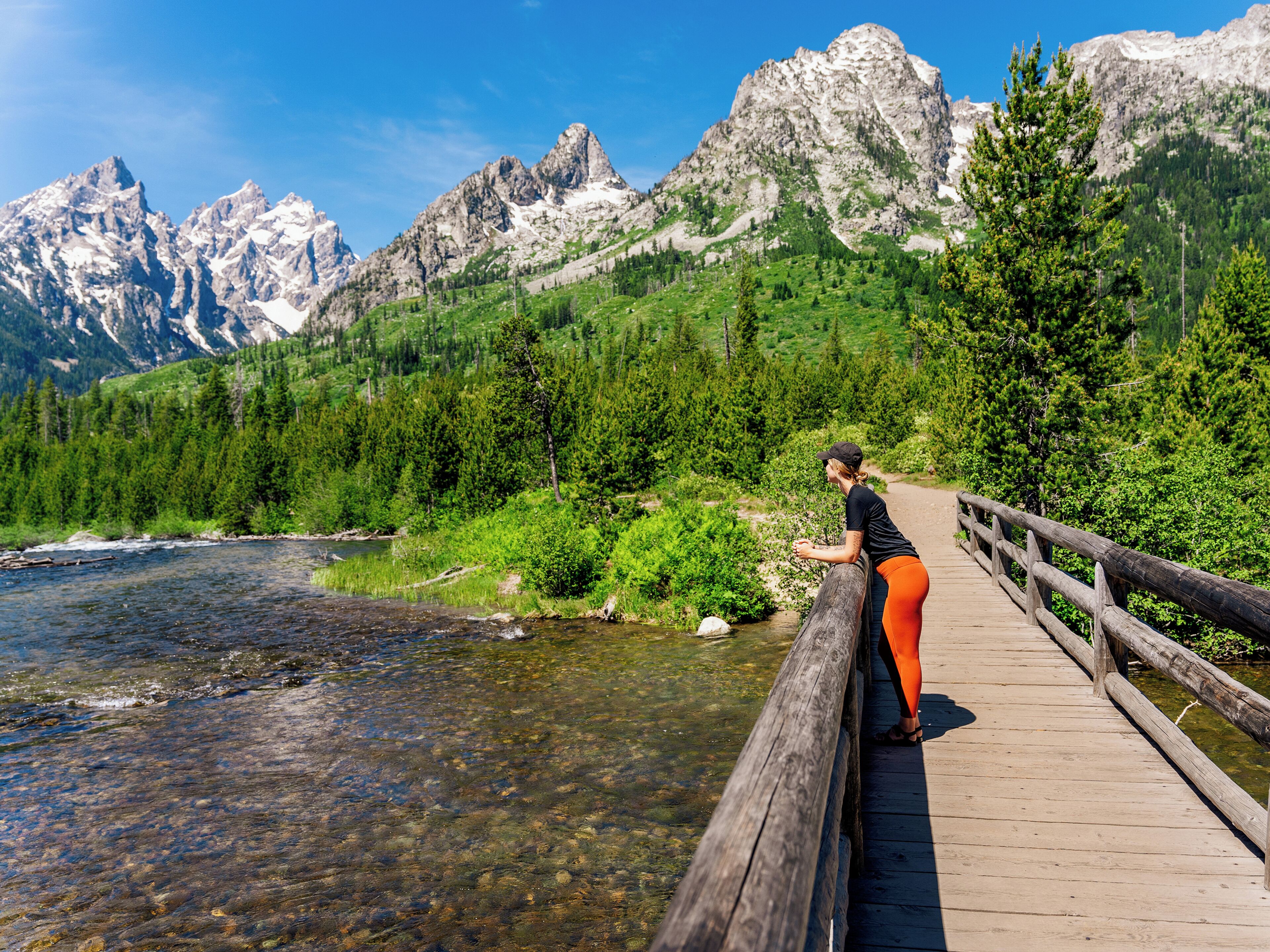 Un puente de madera sobre un río, con montañas al fondo.