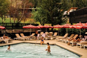 Un área de piscina con sillones de descanso y sombrillas.