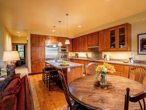 Una cocina con armarios de madera, electrodomésticos de acero inoxidable y una zona de comedor con mesa y sillas de madera.