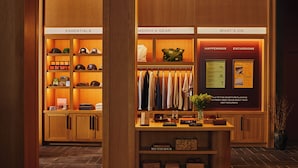 A hotel lobby with wooden paneling, a reception desk, and shelves labeled 'ESSENTIALS,' 'MERCH & GEAR,' and 'WHAT'S ON.' - Residences at Snow King (Jackson)