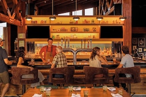 A bar area with wooden furniture and a variety of bottles and glasses on shelves.