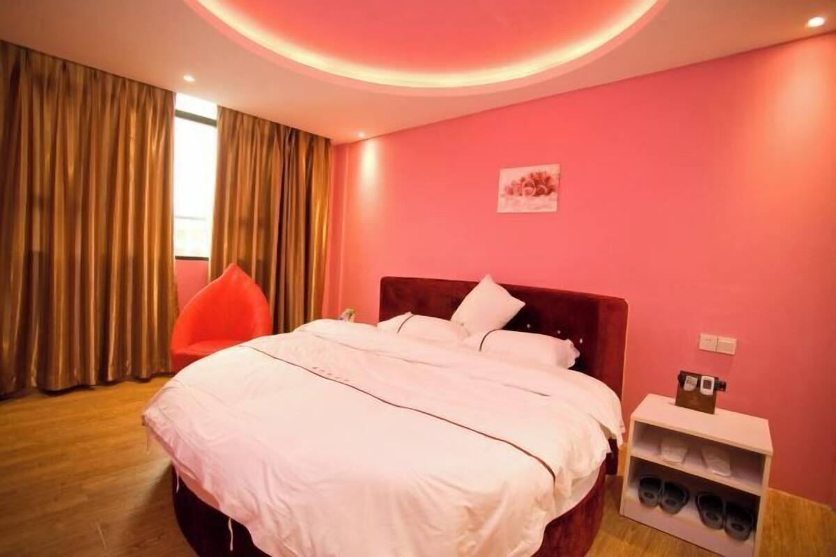 A bedroom with a bed, a chair, a shoe rack, and a wall-mounted light fixture.