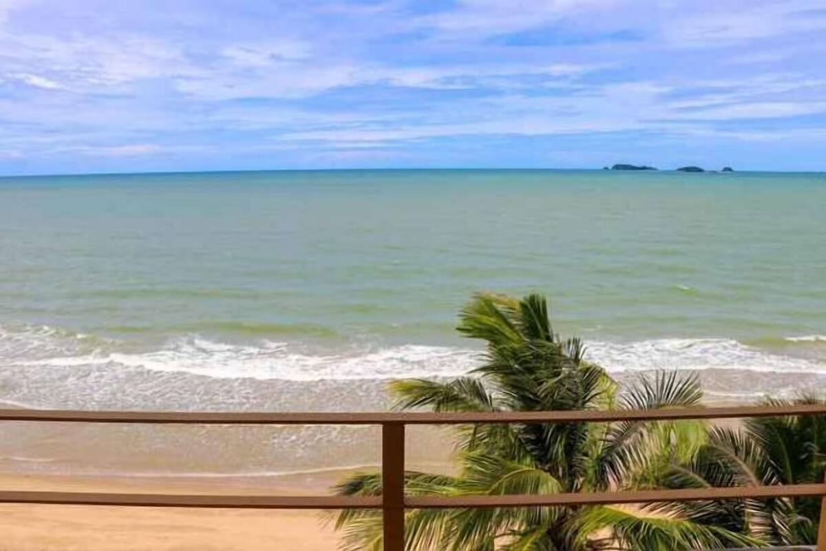 A beach view with palm trees and a clear sky.