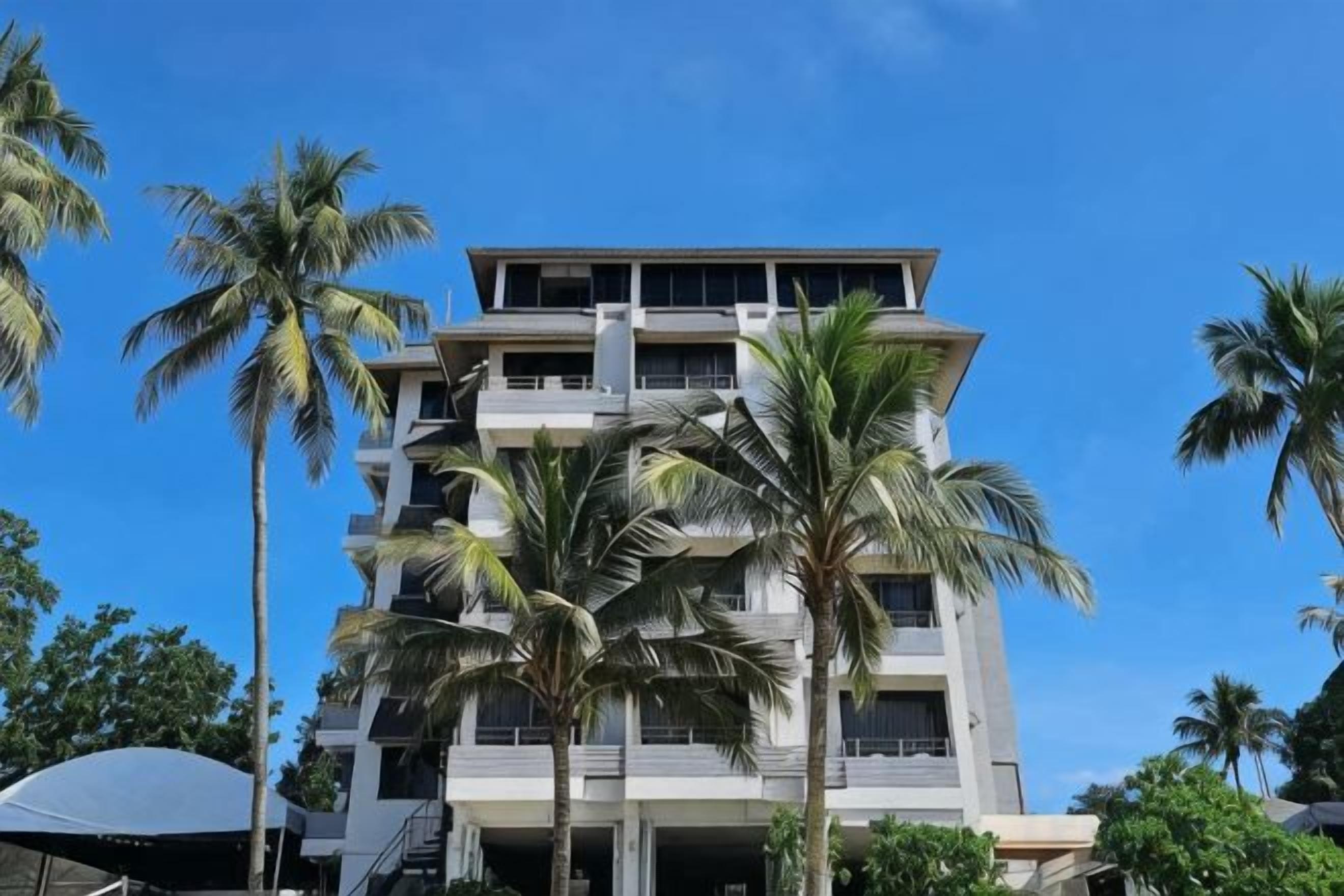 Um hotel com vários andares e design arquitetônico moderno, com varandas e um céu claro.