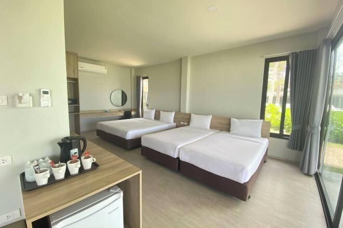 A hotel room with two beds, a desk with a coffee maker, and a large window.