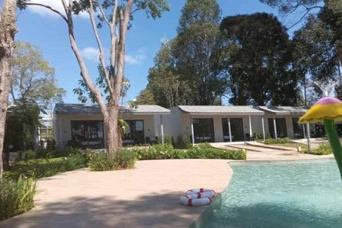 A pool area with a lifebuoy, trees, and a building in the background.