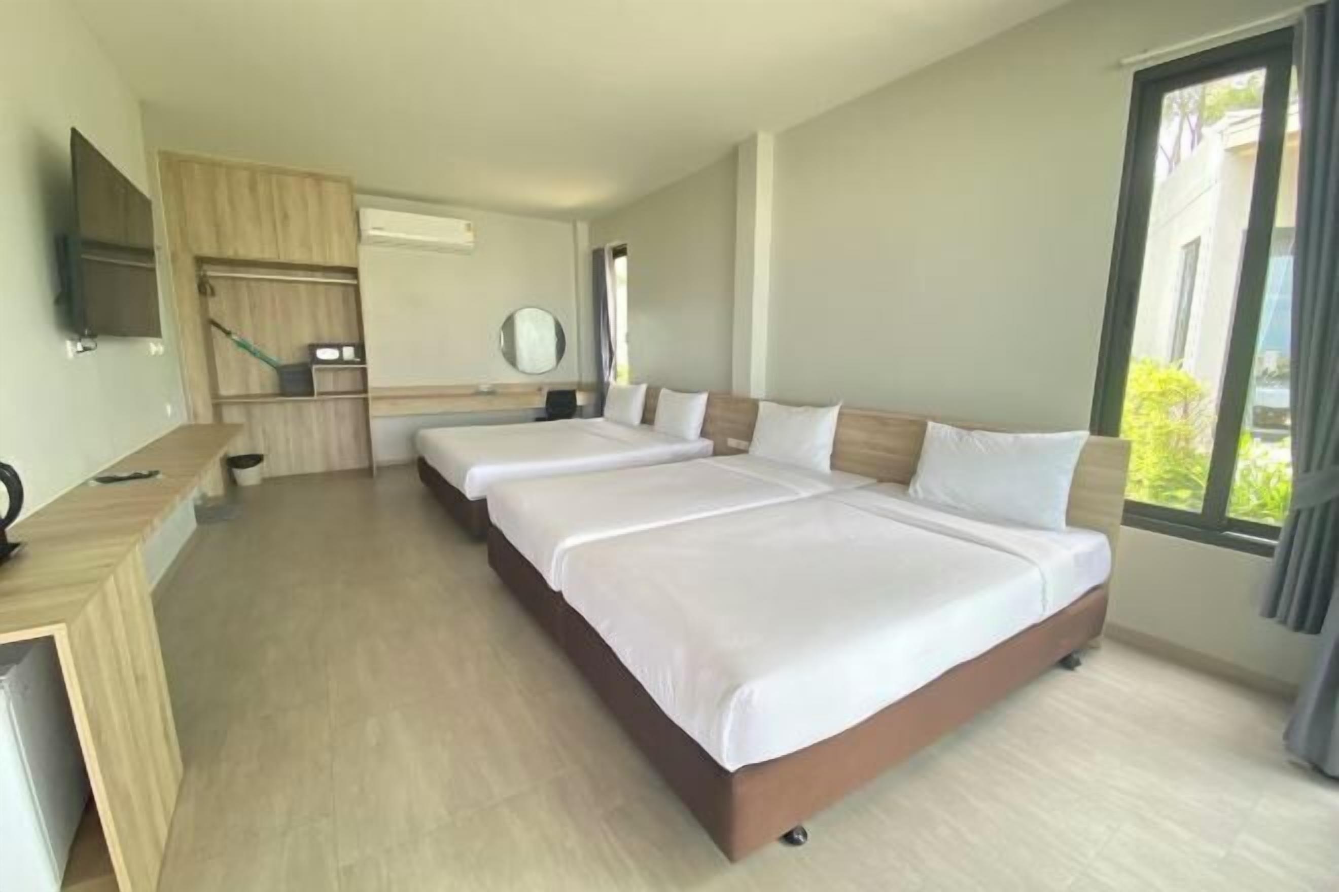 A hotel room with two beds, a desk, a TV, and a large window.