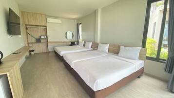 A hotel room with two beds, a desk, a TV, and a large window.