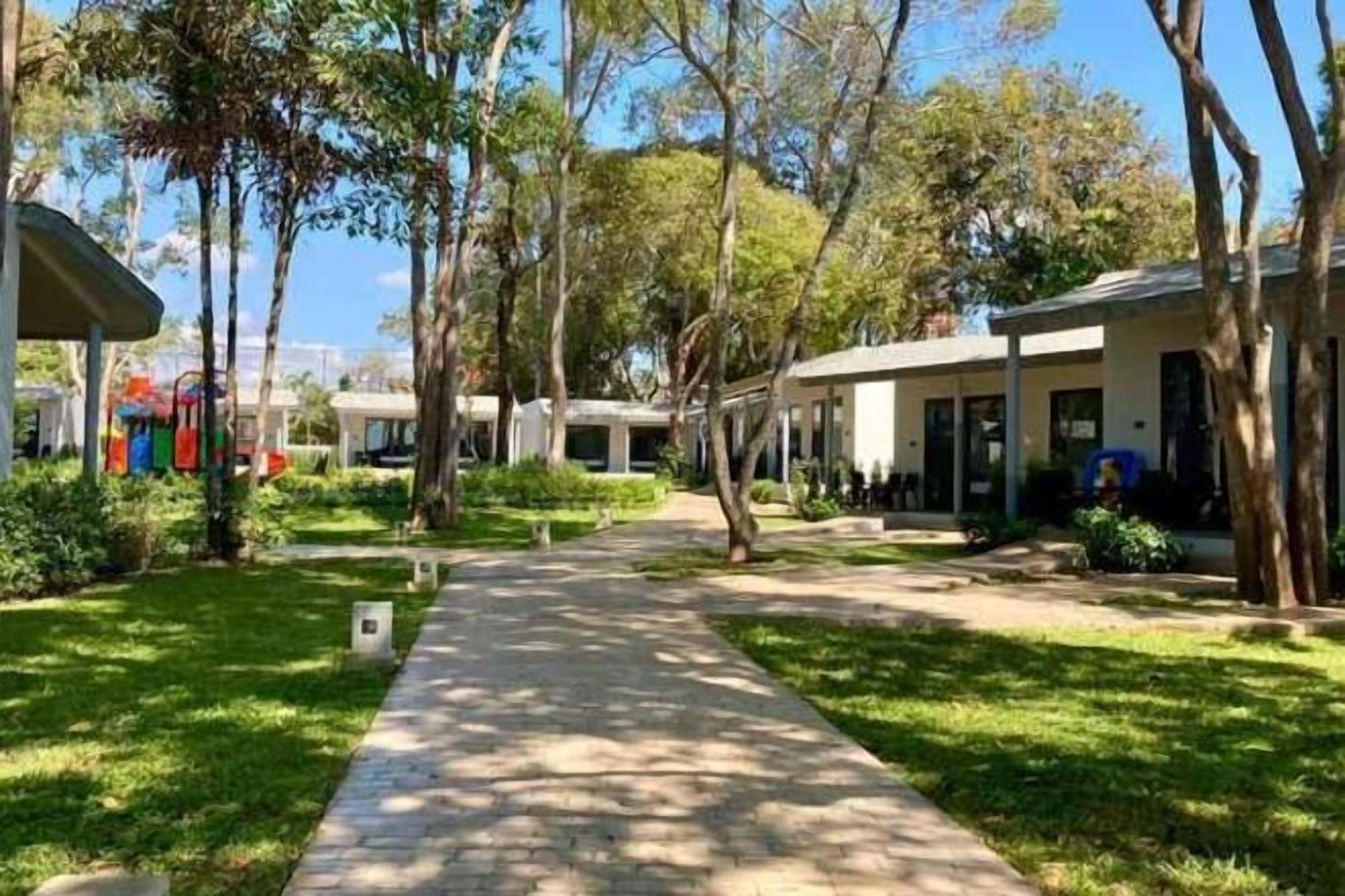 A pathway leading to a row of buildings with a clear sky above.