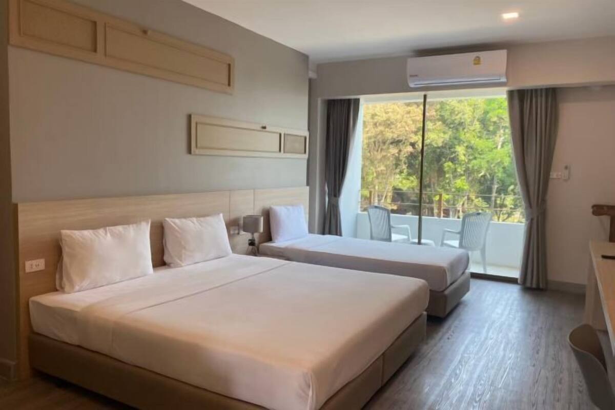 A hotel room with two beds, a balcony with a view, and an air conditioning unit.