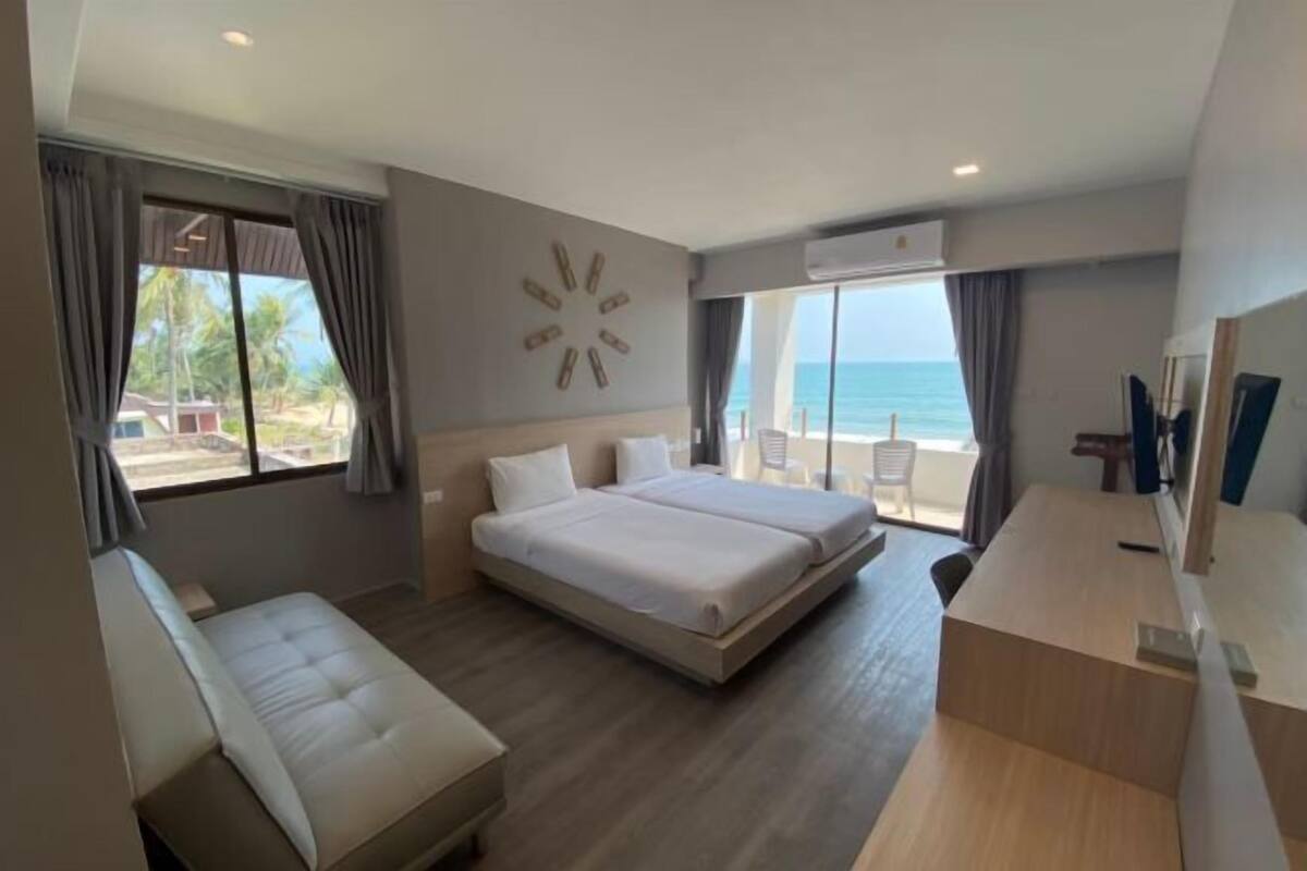 A modern hotel room with a large bed, a desk, and a view of the ocean.