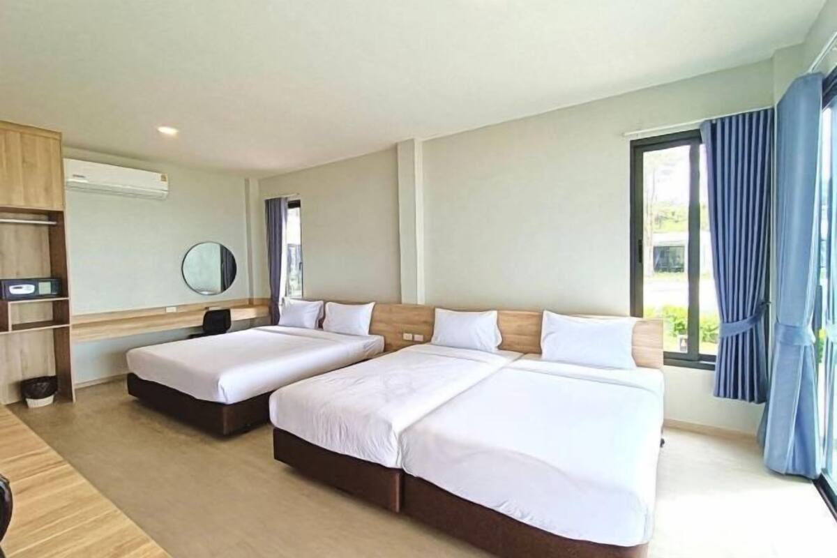 A hotel room with two beds, a desk, a mirror, and a window with curtains.