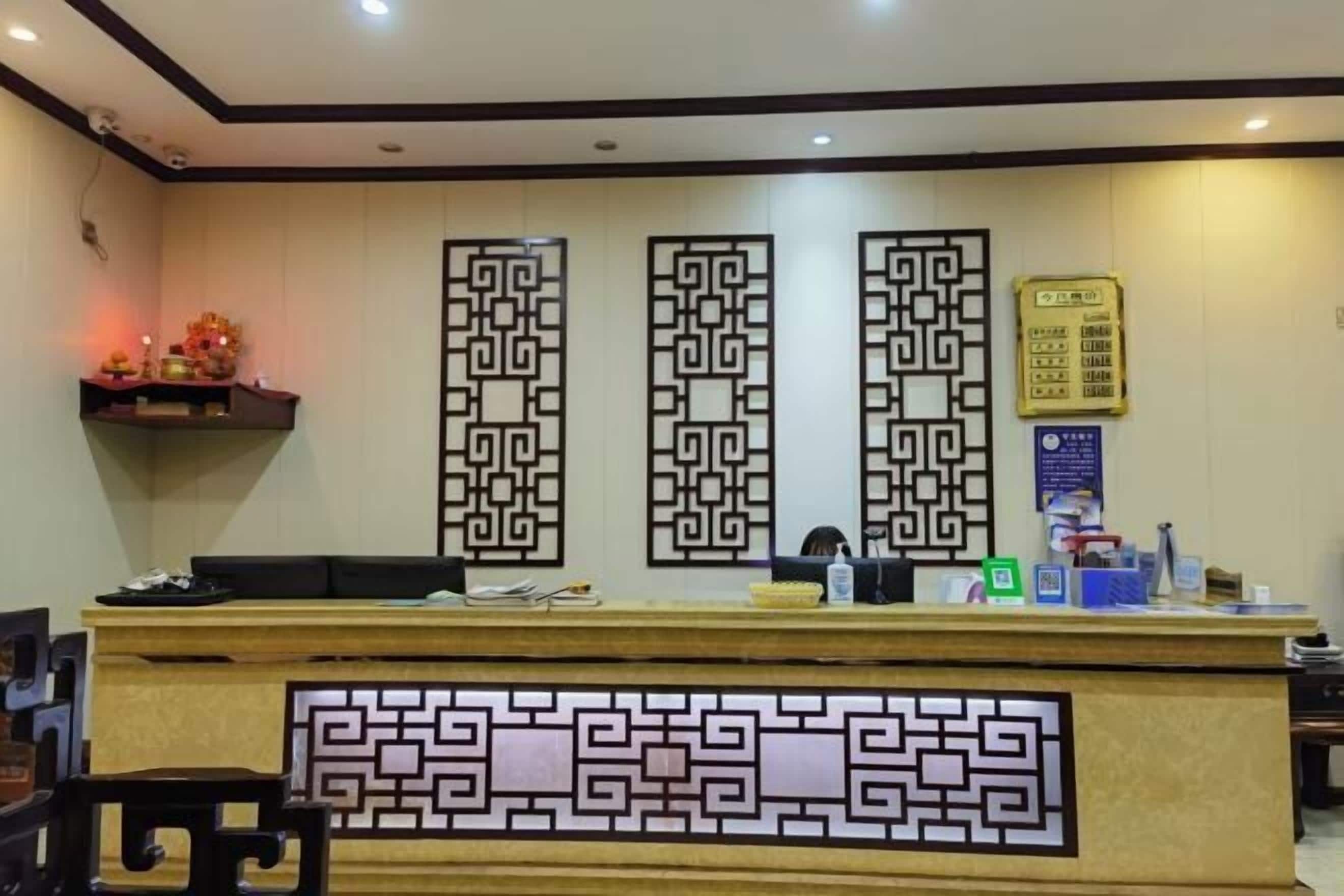 A reception desk with a decorative panel, a computer, and a small shelf with items.