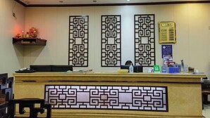 A reception desk with a decorative panel, a computer, and a small shelf with items. - Jiangcheng Lindeng Hotel (Jiangcheng)