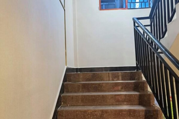 A staircase with a black metal railing, leading to a landing with a window.