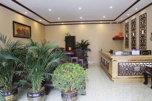 A reception area with a reception desk, potted plants, and a decorative wall panel.