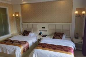 Habitación de hotel con dos camas, cada una con cabecero, mesitas de noche y lámparas.