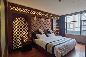 Un dormitorio con una cama grande, cabecera de madera y ventana con vistas.