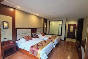 A hotel room with two beds, wooden flooring, a large mirror, and a door. - Jiangcheng Lindeng Hotel (Jiangcheng)