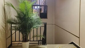 A hallway with a potted plant, a black gate, and a window with geometric patterns. - Jiangcheng Lindeng Hotel (Jiangcheng)