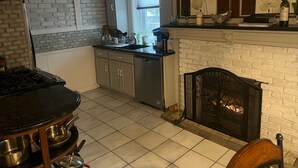 Eine Küche mit Kamin, einem Esstisch und einem fenster mit Vorhängen.