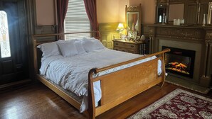 Ein traditionell eingerichtetes Schlafzimmer mit einem hölzernen Himmelbett, einem Kamin und einem Spiegel über dem Schminktisch.