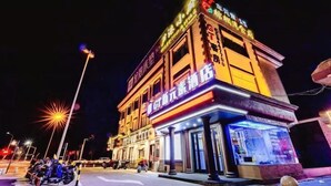 A brightly lit building with illuminated signage, a ground-level entrance, and a visible upper floor with windows. - GT New Element Hotel (Ningbo)