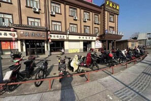 Una fila de motocicletas estacionadas frente a un edificio con varios letreros y cielo despejado.