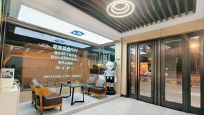 A hotel lobby with a reception desk, seating area, and a large glass window. - GT New Element Hotel (Ningbo)