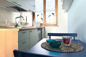 A kitchen with a window, a table with a mat, a glass, and a bowl.