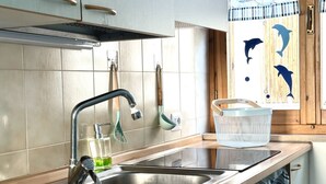 Eine Küche mit einer Edelstahlspüle, Holzschränken und einem Fenster mit Delfin-Motiven.