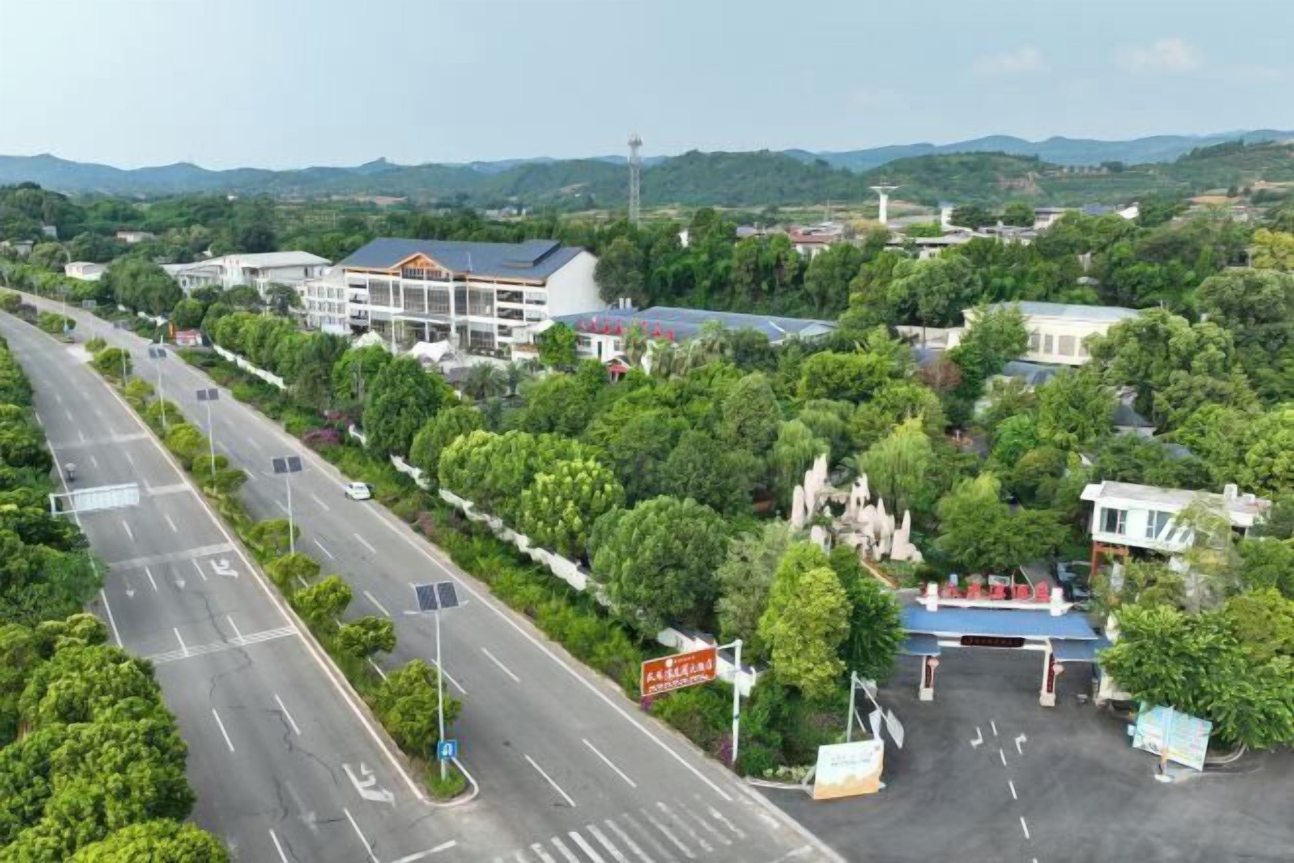 Une route bordée d’une station-service et de bâtiments entourés de verdure.