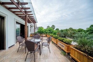 Un patio al aire libre con una mesa, sillas, una pérgola de madera y vista a zonas verdes.