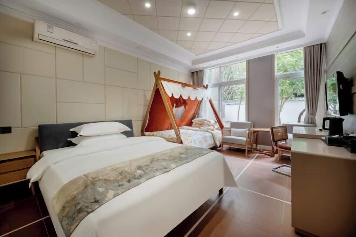 A hotel room with a large bed, a desk, a chair, and a television.