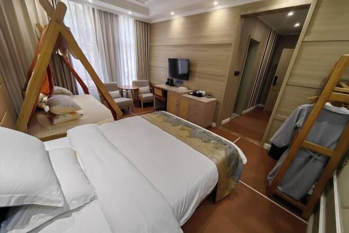 A hotel room with a bed, a desk, a TV, and a wardrobe.