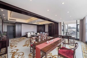 Amplia habitación de hotel con un gran comedor, asientos cómodos y vistas a la ciudad.
