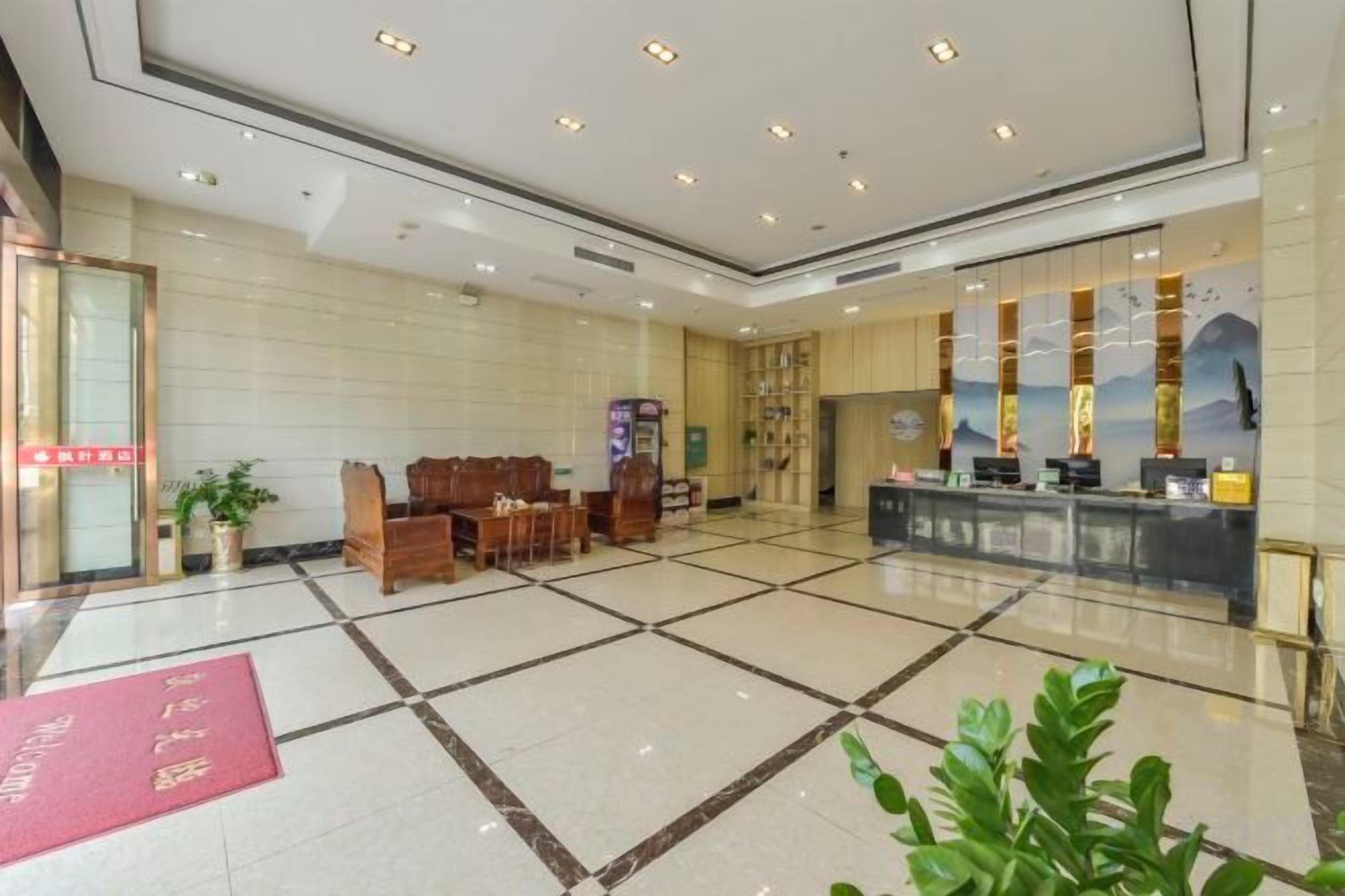 A hotel lobby with a reception desk, seating area, and a large window with a view.