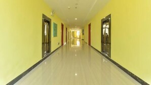 A long, narrow hallway with yellow walls and a shiny floor, leading to a bright room at the end.
