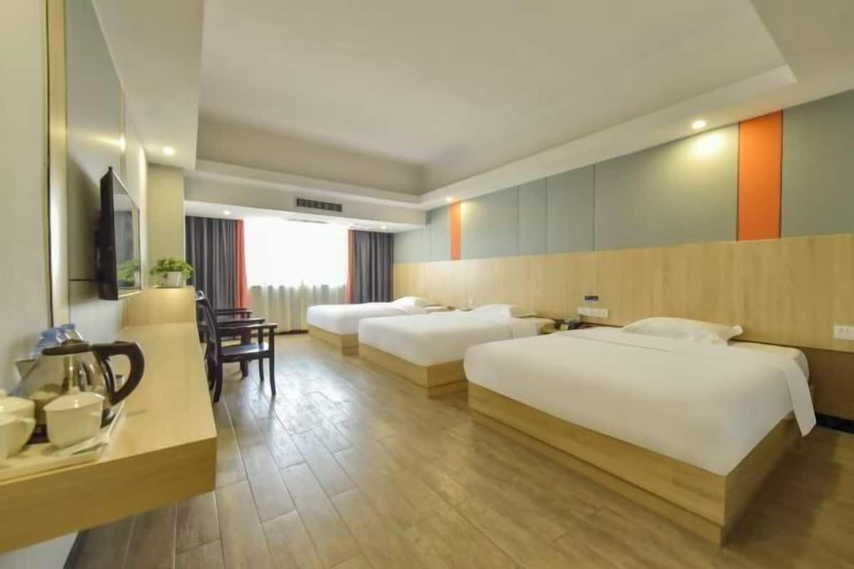 A hotel room with two beds, a desk with a chair, a TV, and a window with curtains.