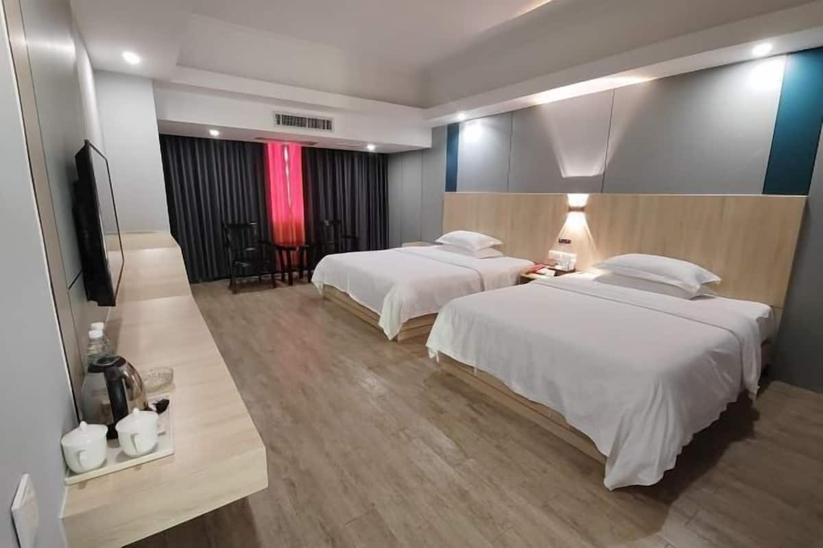 A hotel room with two beds, a TV, a desk with a coffee maker, and a chair.