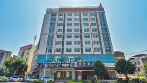 A multi-story hotel with a modern facade, featuring a prominent entrance with glass doors and a signboard.