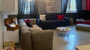 Un salon moderne avec un canapé d’angle, une table basse ronde et un mur d’accent rouge.