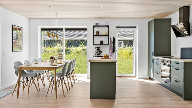 Eine moderne Küche mit einer zentralen Kochinsel, eingebauten Geräten und Blick auf den Garten.